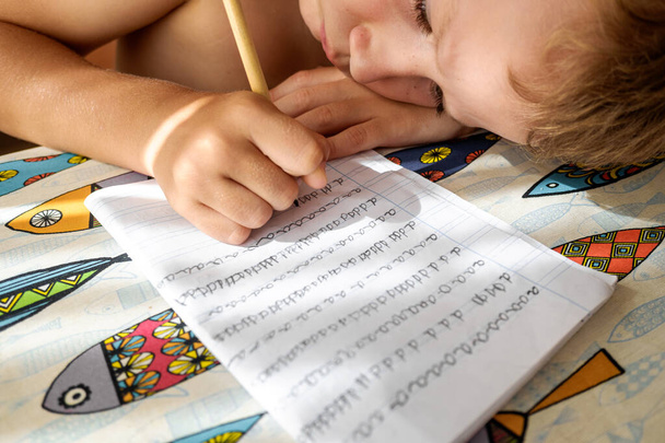 Chłopiec stara się uczyć i odrabiać lekcje podczas wakacji.. - Zdjęcie, obraz