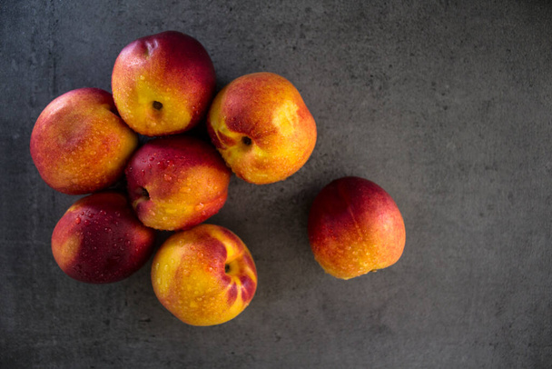 Fresh nectarines on a table. Juicy summer fruits close up photo. Dark grey background with copy space. Healthy eating concept.  - Foto, immagini