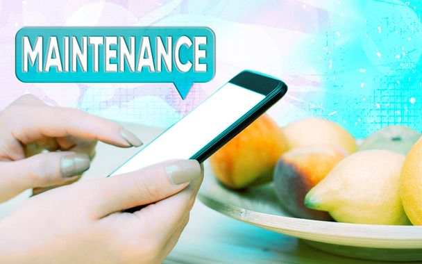 Word writing text Maintenance. Business concept for the process of maintaining or preserving someone or something Modern gadgets with white display screen under colorful bokeh background. - Photo, Image