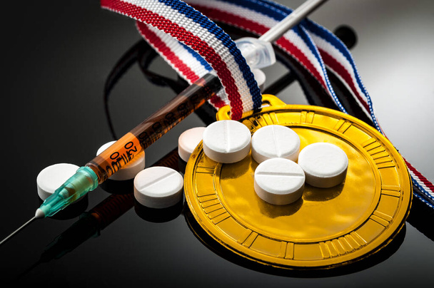 Doping in sport en steroïde misbruik concept met een gouden medaille, recept pillen en een spuit op een donkere achtergrond - Foto, afbeelding