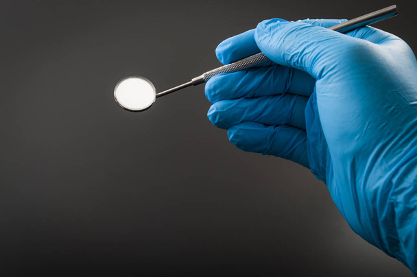 Instrumentos de odontología y concepto de chequeo del higienista dental con una mano dentista que usa guantes de látex azul y sostiene un espejo bucal, un instrumento médico utilizado para verificar si hay caries, con espacio para copiar
 - Foto, imagen