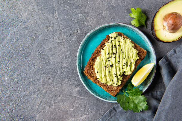 Avocado toast op volkoren brood, puree avocado met sesamzaad en limoen, gezond eetconcept, bovenaanzicht - Foto, afbeelding