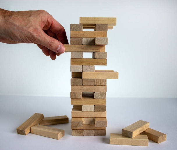 Wood block tower with architecture model. Concept Risk of management and strategy plan, growth business success process and team work. Male hand. Beautiful white background, copy space. - Fotó, kép
