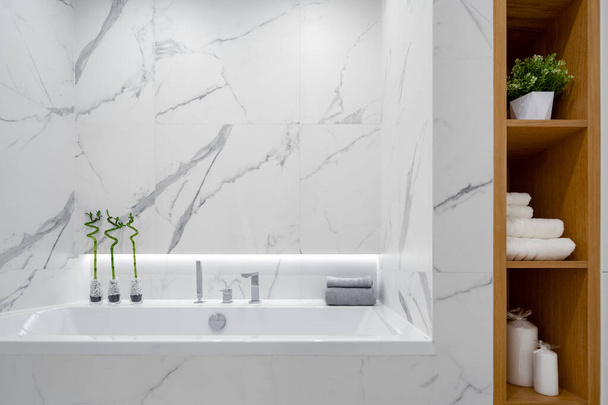 Simple bathtub in elegant and bright bathroom with white marble tiles - Fotografie, Obrázek
