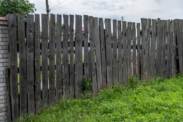 Το παλιό ξεπερασμένο ξύλινο φράχτη κοντά σε κατοικίες. - Φωτογραφία, εικόνα