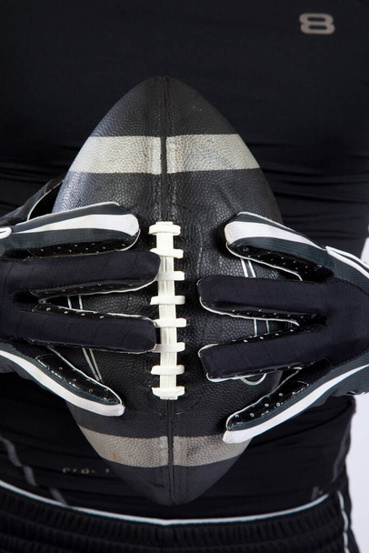 Руки в рукавичці з чорним американським футболом, - Фото, зображення