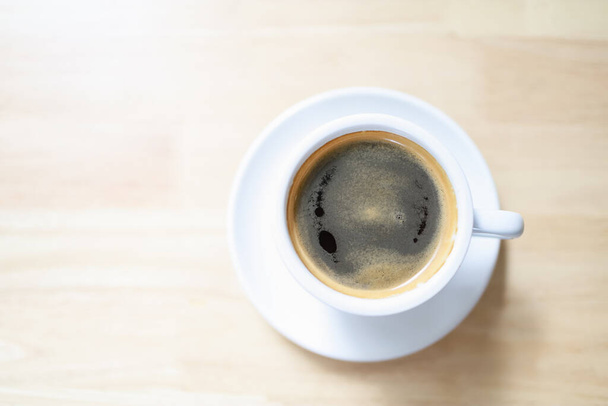 Bovenaanzicht van witte kop hete zwarte koffie en crema op witte tafel . - Foto, afbeelding