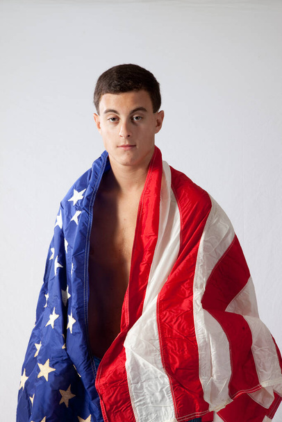 Un hombre sin camisa pensativo envuelto en una bandera de los Estados Unidos - Foto, Imagen