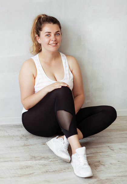 Beautiful smiley sporty woman sitting on the floor and relaxing - Φωτογραφία, εικόνα