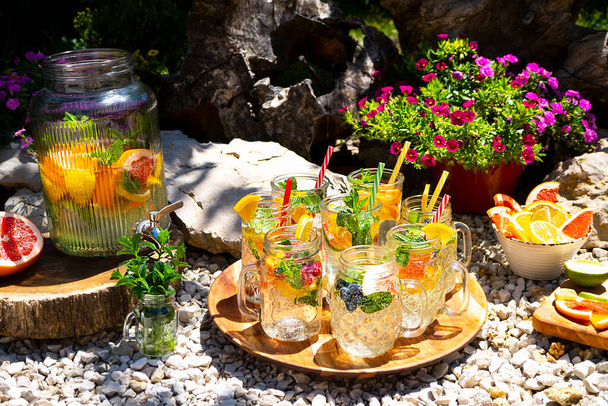 White sangria with fruit and ice in beautiful cocktail mugs stands on a round wooden tray. Nearby is a large jug with a crane with sangria. Summer cool drinks. Beautifully designed catering - 写真・画像