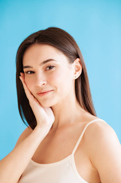 Portrait of lovely young woman with healthy skin against blue background. Daily beauty routine - Foto, afbeelding