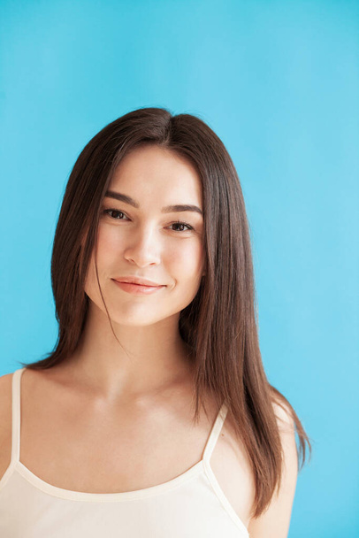 Portrait of lovely young woman with healthy skin against blue background. Daily beauty routine - Fotó, kép
