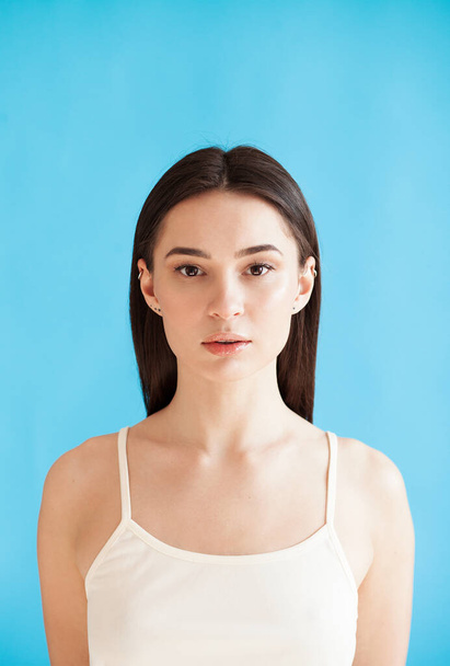 Portrait of beautiful young woman with healthy smooth skin against blue background. Daily beauty routine - Photo, Image
