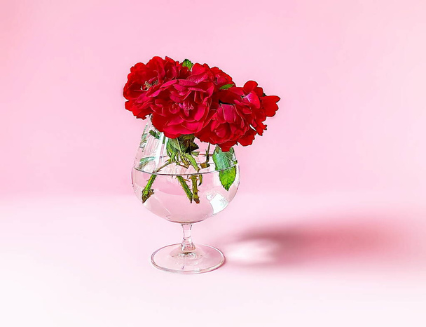 red roses bouquet in glass vase on pink background  floral template background festive greetings card valentine women day copy space  - Fotoğraf, Görsel