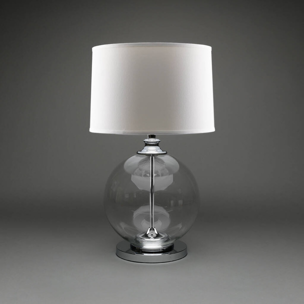 Individula Kugeltischlampe aus klarem Glas mit weißem Lampenschirm auf dunkelgrauem Hintergrund. - Foto, Bild