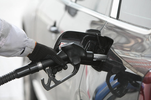 Hand holding fuel nozzle to add gas. Car refueling on a petrol station. Fuel, energy, ecology concept. - Fotoğraf, Görsel