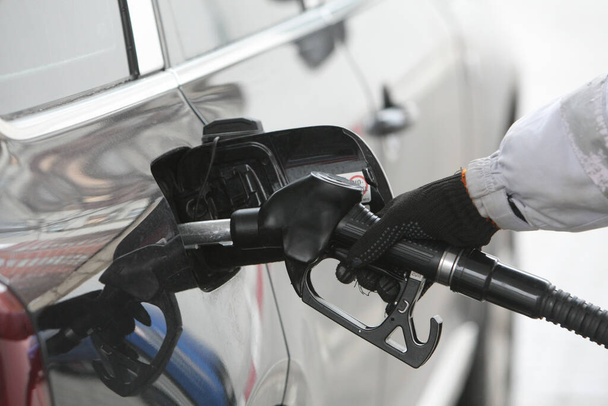 Hand holding fuel nozzle to add gas. Car refueling on a petrol station. Fuel, energy, ecology concept. - Foto, afbeelding
