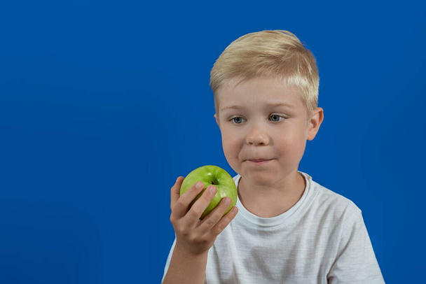 Bebek yeşil bir elmaya bakıyor. Sağlıklı gıda - Fotoğraf, Görsel