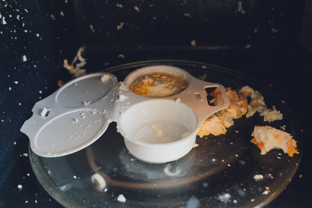 Eierexplosie in de magnetron. Fragment van een plastic bakje voor het koken van eieren in de magnetron. - Foto, afbeelding