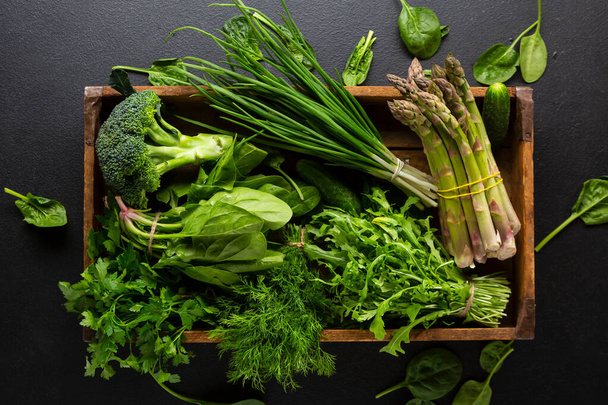Organic green vegetable in wooden crate top view on dark stone background - Fotografie, Obrázek
