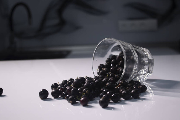 vidro transparente com groselhas em uma mesa branca em uma cozinha cinza
 - Foto, Imagem