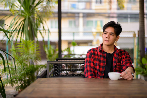 Portrait of young handsome Filipino hipster man relaxing inside the coffee shop - Valokuva, kuva