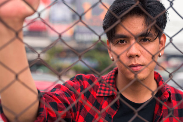 Portrait of young handsome Filipino hipster man in the city streets outdoors - Foto, afbeelding