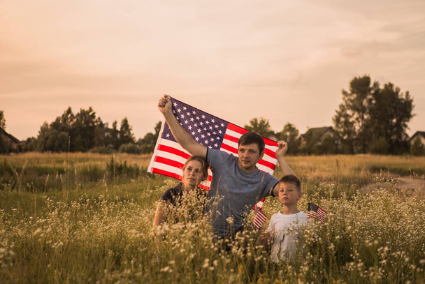 Amerikkalainen päästää Amerikan lipun liehumaan tuulessa viheriöllä. Isänmaallinen perhe juhlii USA itsenäisyyspäivä 4. heinäkuuta. Perustuslaki ja Patriot Day. - Valokuva, kuva
