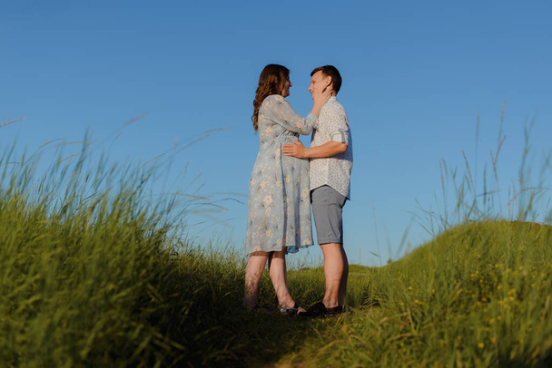 Glückliches junges Paar küsst sich auf einem Berg, mit klarem Himmel im Hintergrund - Foto, Bild