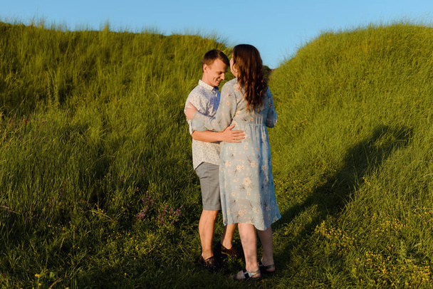 Junge fröhliche Paar von Mann und Frau im Freien in einem Feld, umarmen und tanzen - Foto, Bild