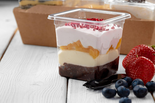 Creamy dessert in a plastic box on wooden table - Photo, Image