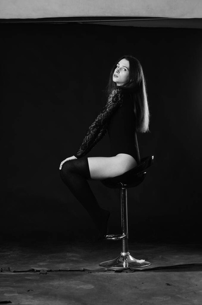 gyönyörű barna fiatal nő fekete testruha pózol sötét stúdió háttér  - Fotó, kép