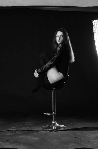bela morena jovem mulher no preto bodysuit posando no escuro estúdio fundo
  - Foto, Imagem