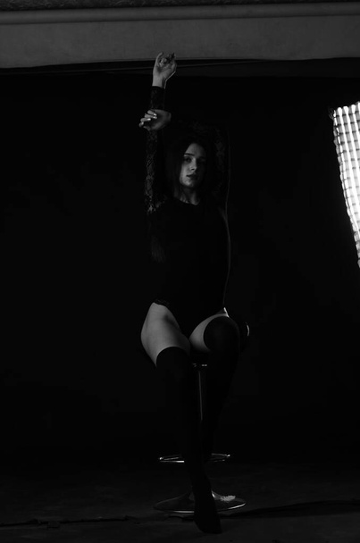 belle brune jeune femme en body noir posant sur fond sombre studio  - Photo, image