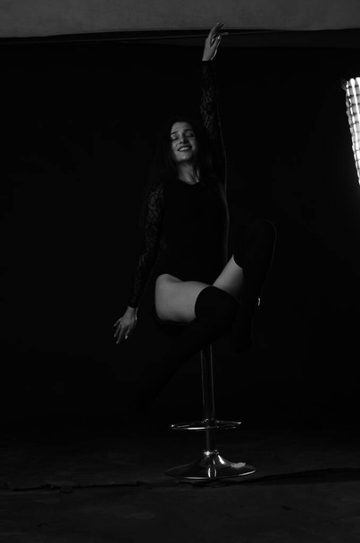 hermosa morena joven mujer en negro bodysuit posando sobre oscuro estudio fondo
  - Foto, Imagen