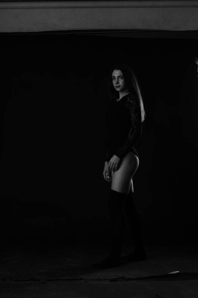 piękna brunetka młoda kobieta w czarnym body pozowanie na ciemnym tle studio  - Zdjęcie, obraz