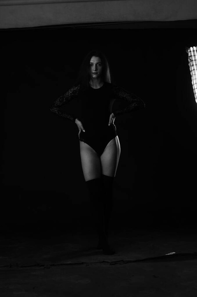 beautiful brunette young woman in black bodysuit posing on dark studio background  - Fotó, kép