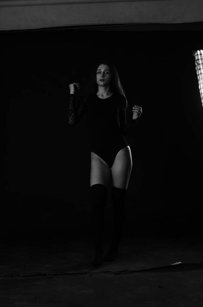 beautiful brunette young woman in black bodysuit posing on dark studio background  - Photo, Image