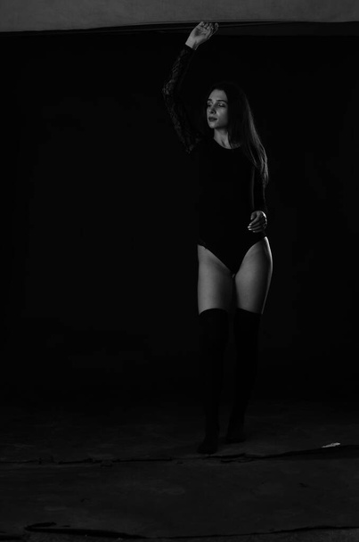 beautiful brunette young woman in black bodysuit posing on dark studio background  - Foto, Imagem