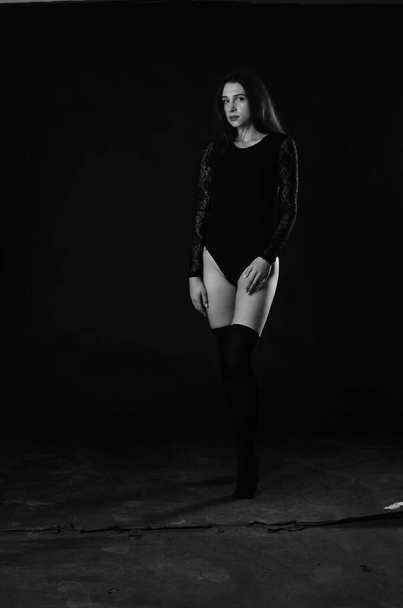 beautiful brunette young woman in black bodysuit posing on dark studio background  - Fotó, kép