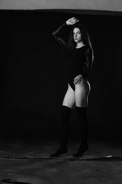 beautiful brunette young woman in black bodysuit posing on dark studio background  - Foto, Imagem