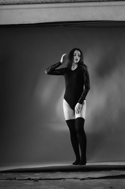 beautiful brunette young woman in black bodysuit posing on dark studio background  - Valokuva, kuva