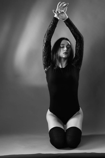 hermosa morena joven mujer en negro bodysuit posando sobre oscuro estudio fondo
  - Foto, imagen