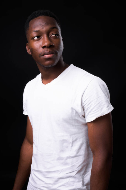 Studio shot of young handsome African man with Afro hair against black background - Fotografie, Obrázek