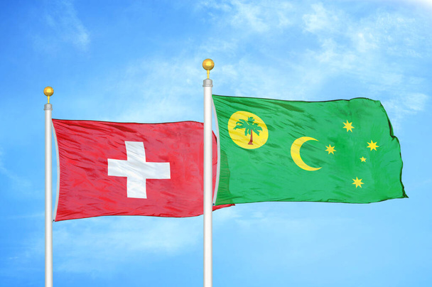 Sveitsi ja Kookossaaret Keeling kaksi lippua lipputangot ja sininen pilvinen taivas tausta - Valokuva, kuva