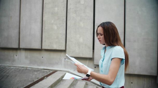 Businesswoman examining financial statistics outdoors. Woman going for work - Фото, изображение