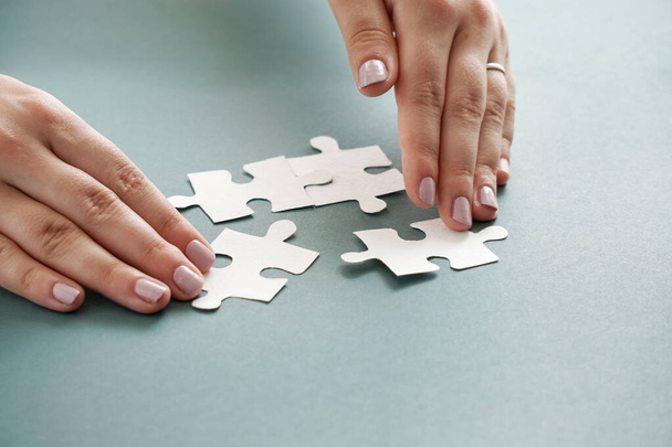 Concepto de negocio, manos de mujeres sosteniendo piezas de rompecabezas blanco en el fondo azul
 - Foto, Imagen