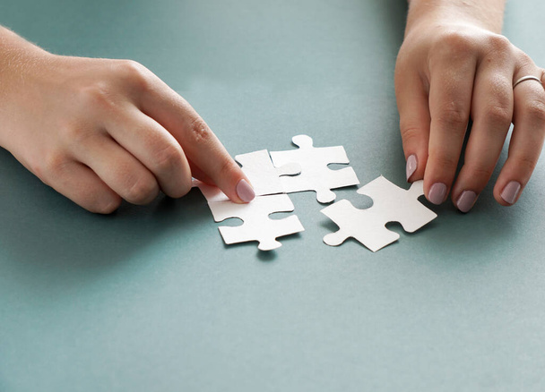 Concept d'entreprise, les mains des femmes tenant des pièces de puzzle blanc sur le fond bleu - Photo, image