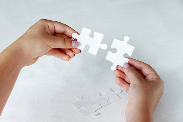 Концепція бізнесу, жіночі руки тримають білі шматочки головоломки на синьому фоні
 - Фото, зображення