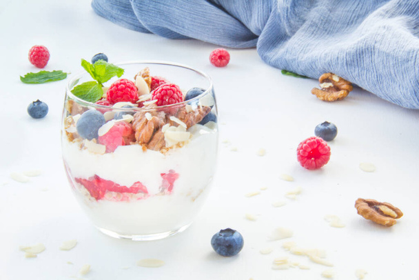 Healthy blueberry, raspberry and walnut parfait in a glass on a white background - Photo, Image